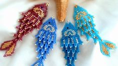 three beaded fish ornaments are shown on a white sheet