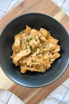 a black bowl filled with food on top of a wooden cutting board