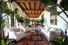 a living room filled with white couches and potted plants