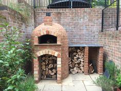 an outdoor brick oven with firewood stacked in it