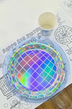 a colorful plate sitting on top of a table next to a cup