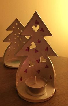 two white candlesticks with hearts on them sitting on a table next to each other