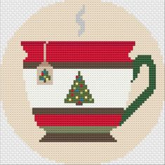 a cross stitch christmas ornament with a tree in a tea cup on it