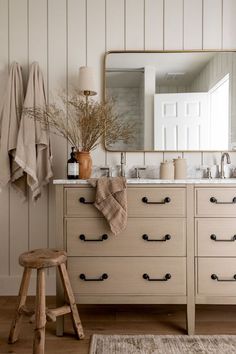 a bathroom with white walls and wooden furniture, including a large mirror over the sink