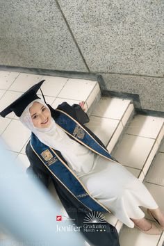 a woman in a graduation gown sitting on some stairs