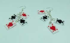 two pairs of earrings with red and black dices on them, hanging from silver hooks