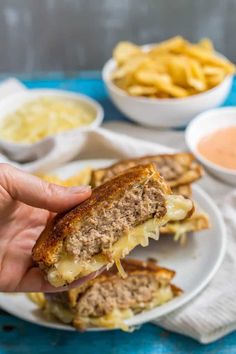 a person is holding up a sandwich with cheese and meat