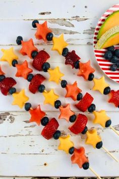 fruit skewers with stars and berries on them next to a bowl of fruit