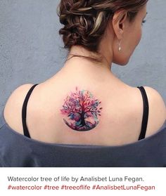 the back of a woman's shoulder with a colorful tree tattoo on it