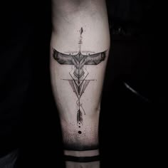 a black and white photo of a cross tattoo on the left leg with an arrow