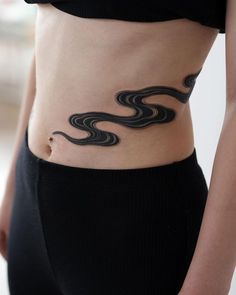 a woman's stomach with an artistic tattoo on her belly and the shape of a wave