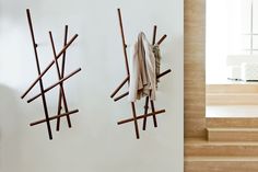 two pieces of art made out of sticks and cloths hanging on the wall next to each other