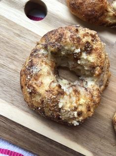 two doughnuts sitting on top of a wooden cutting board