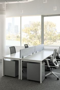 an empty conference room with two desks and chairs in front of large windows overlooking the city