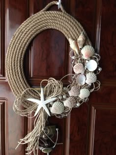 a rope wreath with seashells and starfish hanging on a wooden door handle