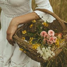 a woman holding a basket with flowers in it