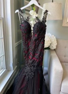 a dress hanging on a hanger in front of a white chair with flowers and a lamp