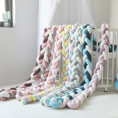 a baby crib with many different colored chains hanging from it's sides and on the floor