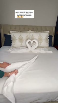 a woman laying on top of a bed with two swans made out of towels in front of her