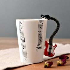 a coffee cup with musical notes on it and a red guitar in the bottom right corner