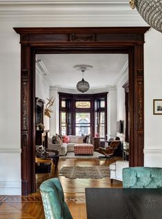 a living room filled with furniture and lots of wood flooring next to a doorway