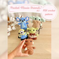 a hand holding a small crocheted animal in front of several smaller stuffed animals