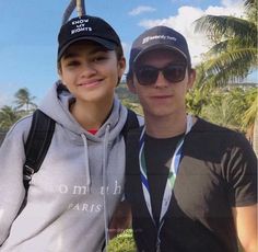 two young men standing next to each other in front of palm trees and blue sky