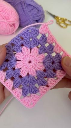 someone is holding a crochet square in their hand