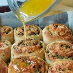 bread rolls with cheese being drizzled over them