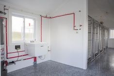 an empty room with pipes and water heaters on the wall next to a window