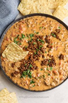 a bowl of chili cheese dip surrounded by tortilla chips