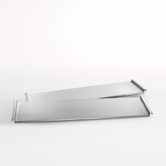 two metal trays sitting side by side on a white surface, one is empty