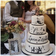 a wedding cake sitting on top of a table next to a vase filled with flowers