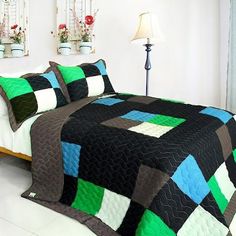 a bedroom with a bed covered in a black and green quilted bedspread