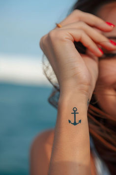 a woman with a small anchor tattoo on her wrist