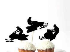 three cupcakes with black silhouettes of people on snowmobiles and one is riding a ski - doo