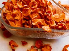 a glass bowl filled with orange peels on top of a white counter next to a spoon