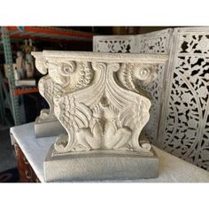 two white marble vases sitting on top of a table in a room with intricate carvings