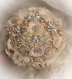 the bridal bouquet is adorned with crystal and pearled brooches, which are embellished with swaroons