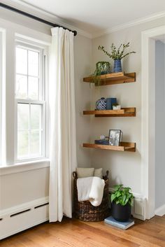 some shelves with plants and pictures on them in a living room next to a window