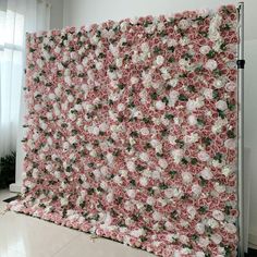 a large pink and white flowered wall hanging on the side of a building in front of a window