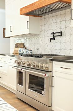 a stove top oven sitting inside of a kitchen next to white cupboards and drawers