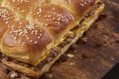 a wooden cutting board topped with cheeseburger sliders