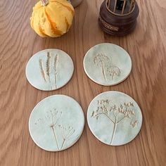 four ceramic coasters sitting on top of a wooden table