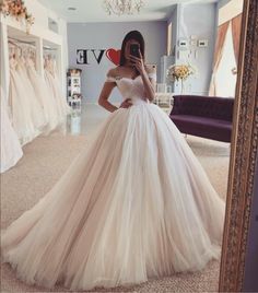 a woman taking a selfie in front of a mirror wearing a white wedding dress