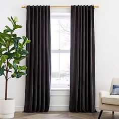 a living room with a couch, chair and large window covered in black drapes