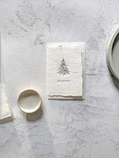 a white table topped with plates and napkins next to a cup filled with liquid