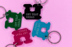 four different colored keychains with the words get that bread on them, and one has a hole in the middle