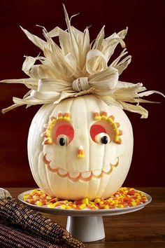 a pumpkin decorated with corn on top of a plate