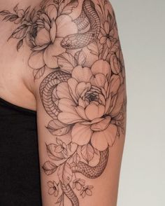 a woman's arm with flowers and a snake on the back of her shoulder